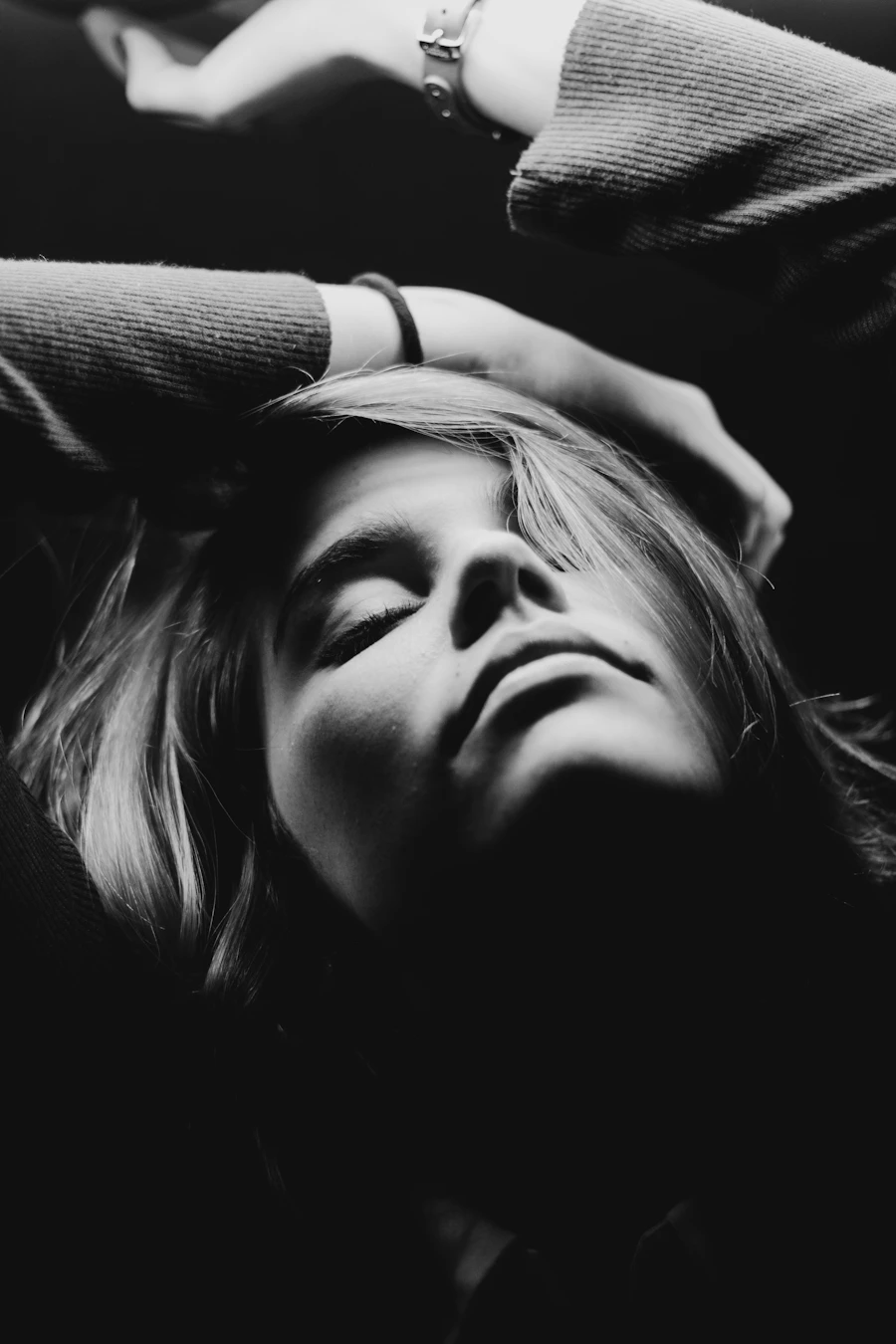 Woman with closed eyes and hands in her hair in black and white