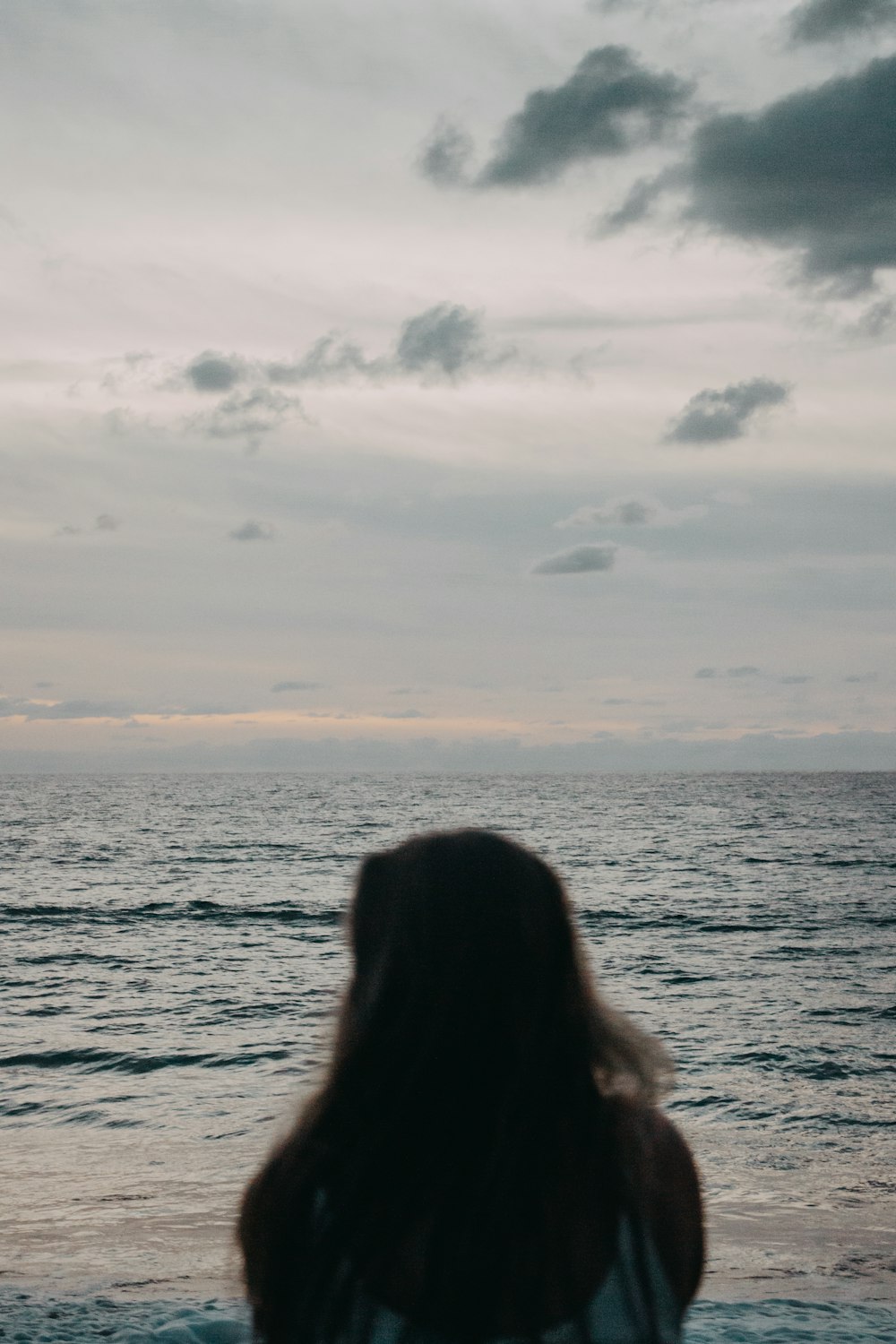 woman wearing white top standing near ocean