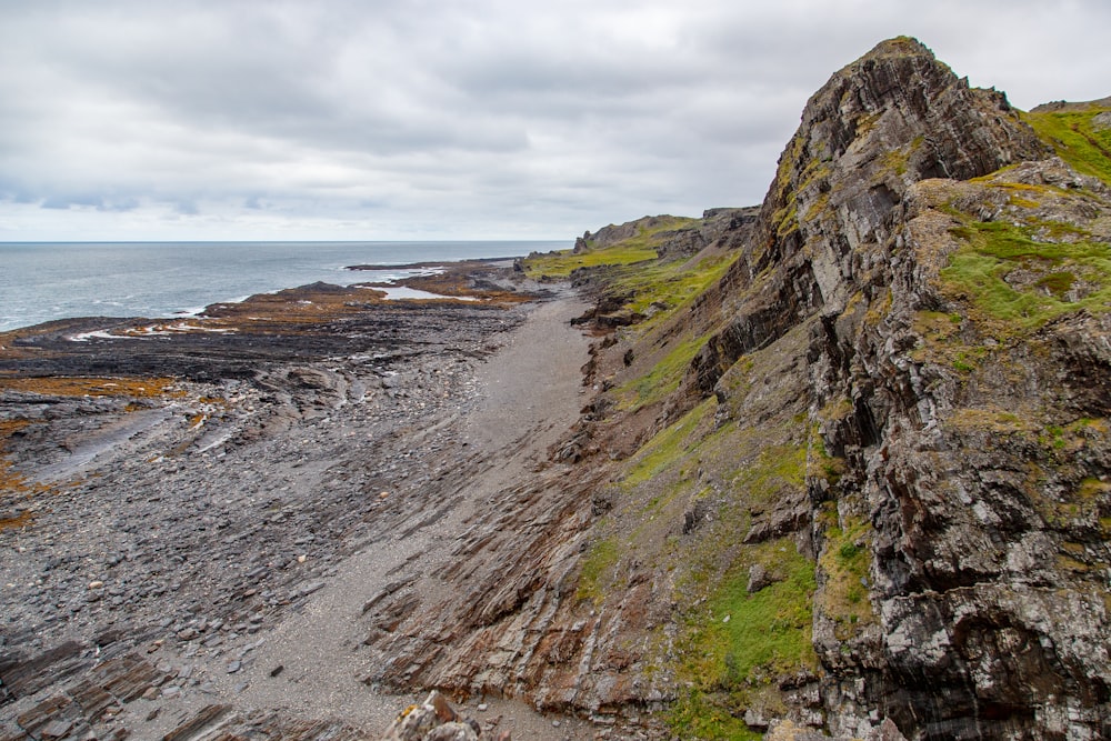 gray and green hill near ocean during daytime