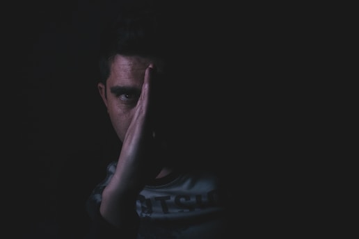 Close-up of a suspicious individual’s face partially obscured by shadows.