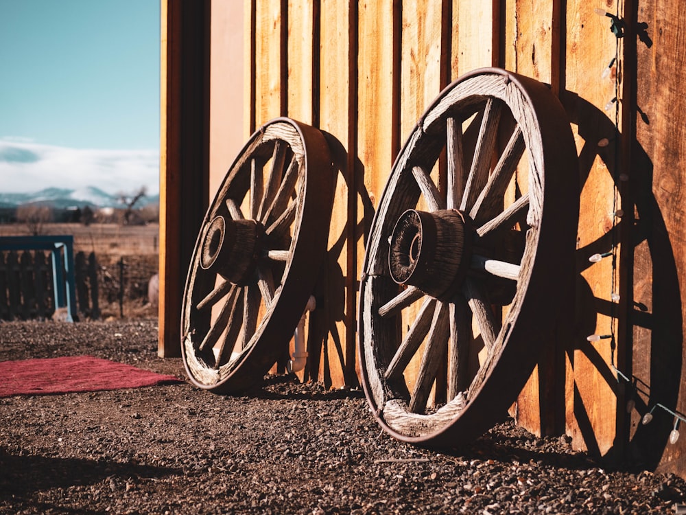 two brown carriage wheels learning on brown house