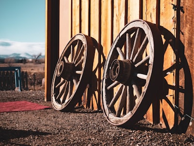 two brown carriage wheels learning on brown house wheel zoom background