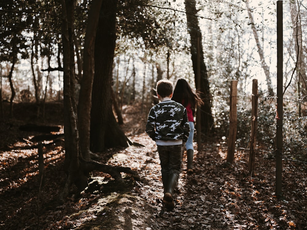 two children walking on forest during daytime