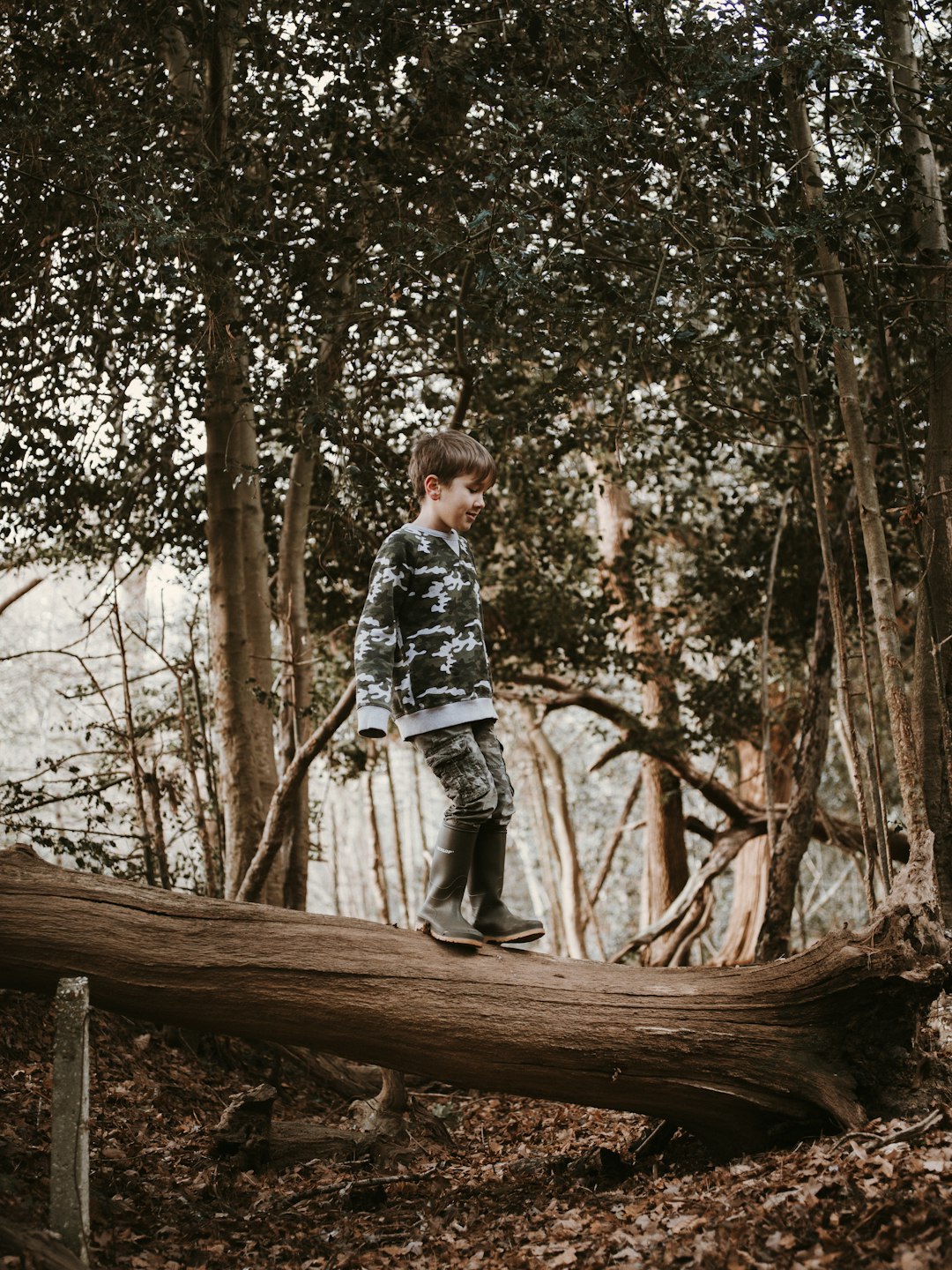 boy standing on wood log during daytime