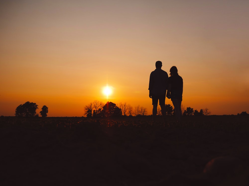 couple stands on field during golden hour