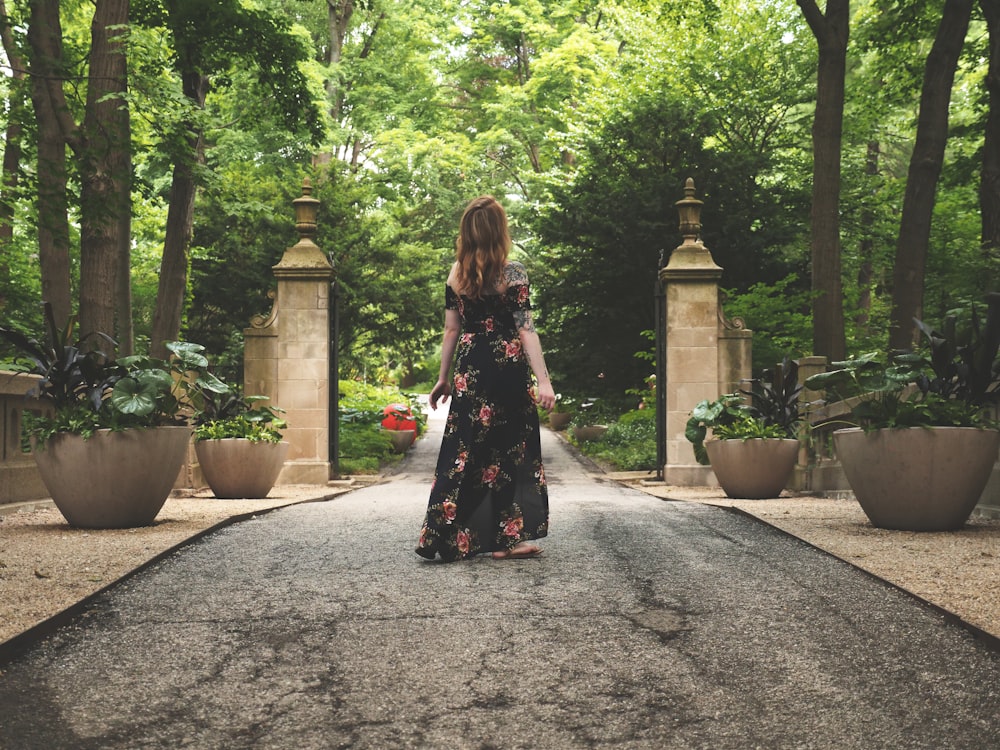 woman in black and pink floral dress standing near plants