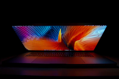 Sleek laptop screen panel reflecting neon blue light on a dark background