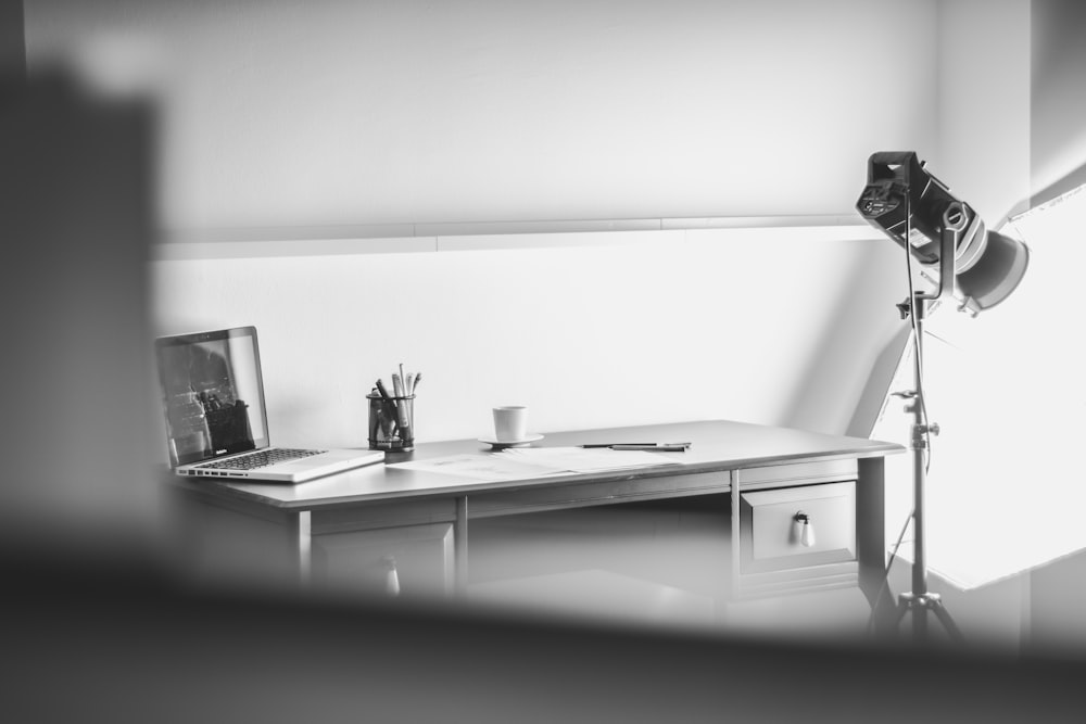 grayscale photography of MacBook Pro on desk