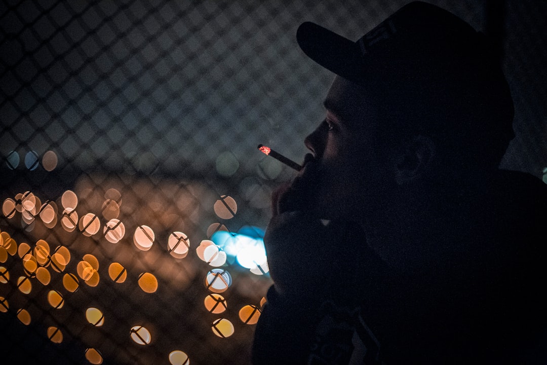 man smoking beside fence