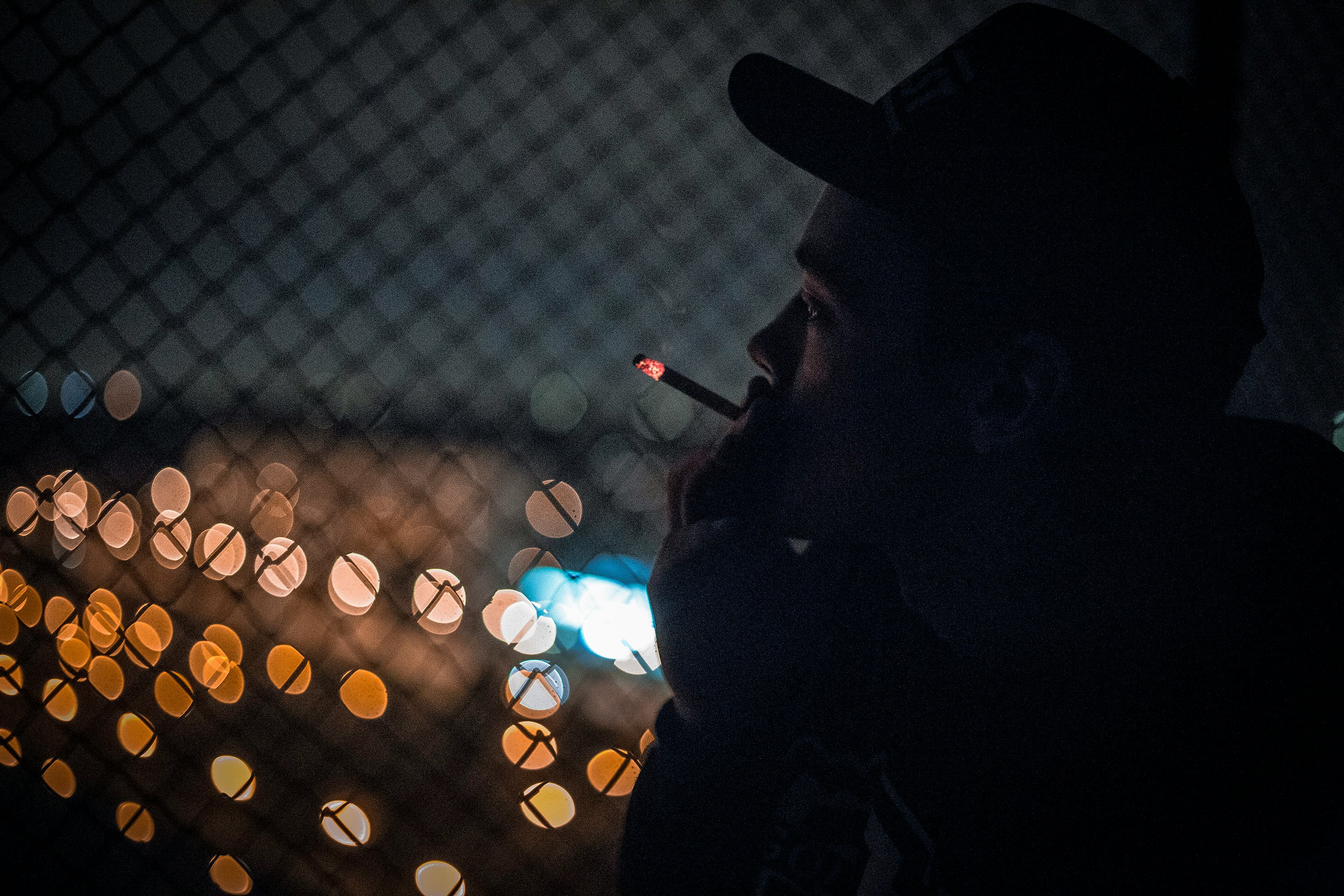 man smoking beside fence