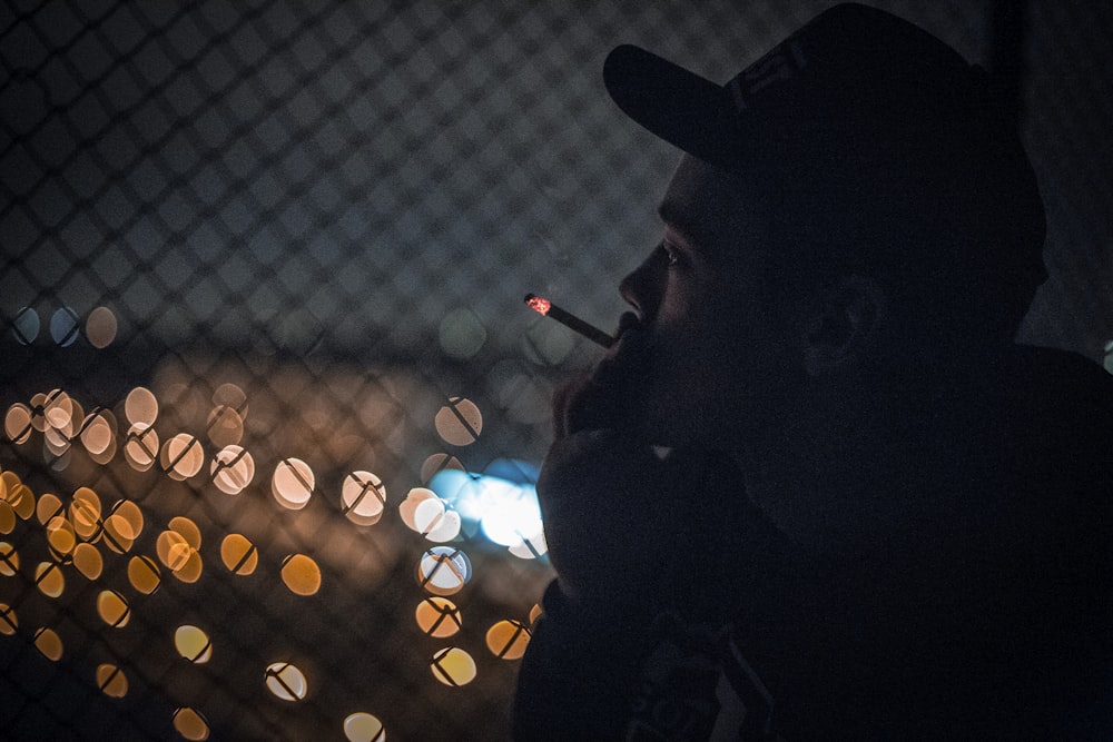 man smoking beside fence