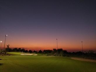 Luxurious golf course at sunset with manicured greens and golden light.