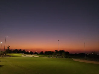 Elegant outdoor golf club event with guests networking at sunset.