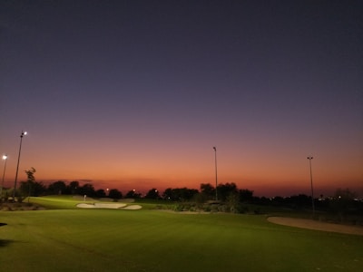 Luxurious golf course at sunset with manicured greens and golden light.