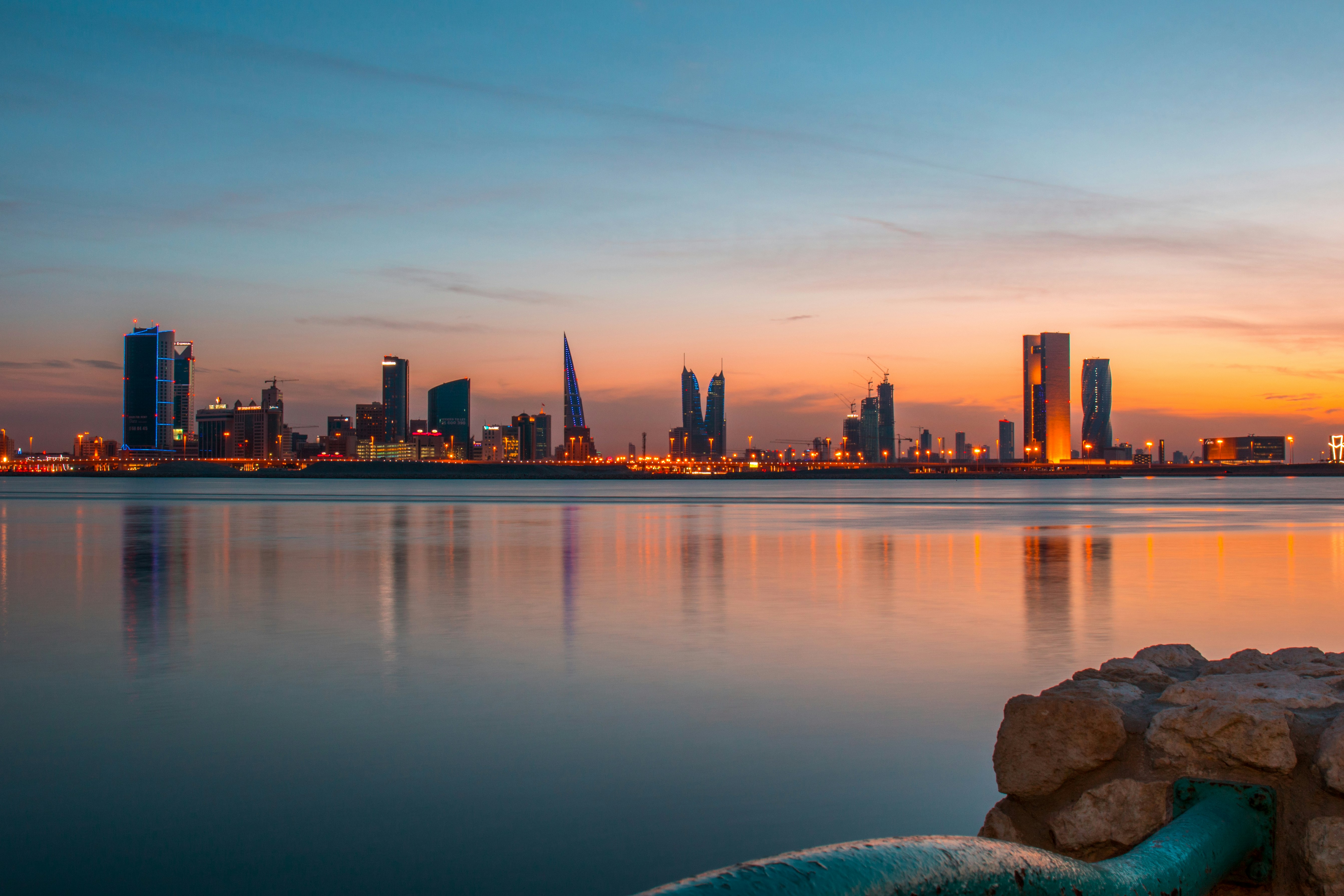 city buildings beside body of water under blue sky