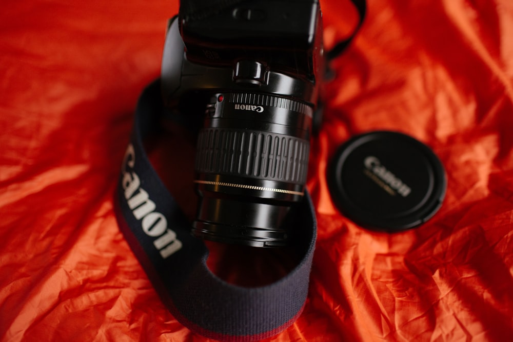 close-up photography of black Canon DSLR camera on red textile