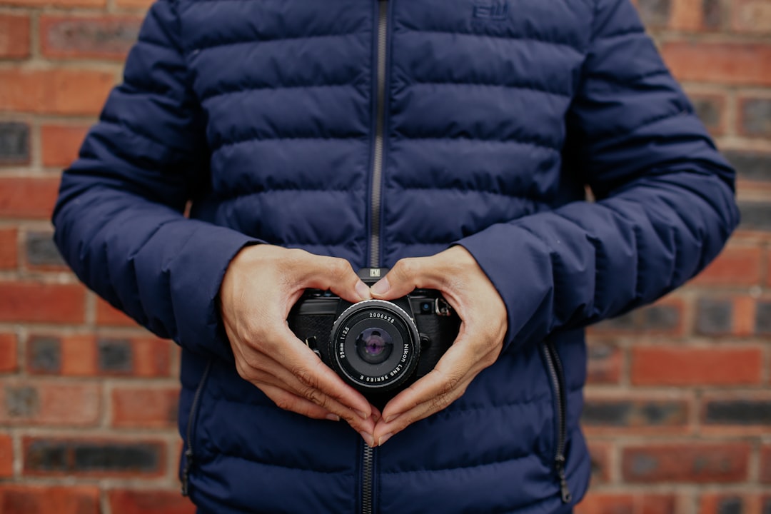 person holding camera wearing blue zip-up jacket