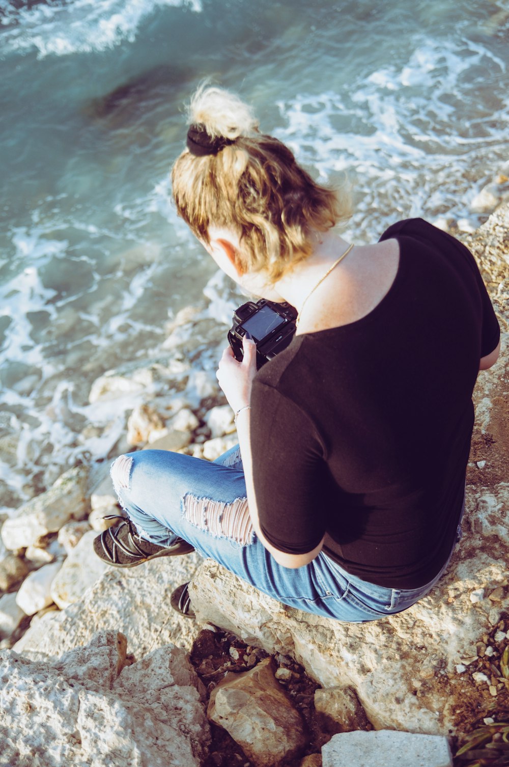 woman sitting on brown stone holding DSLR camera