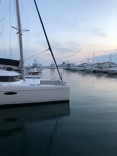 Elegant luxury yacht docked at sunset with calm sea and clear sky.