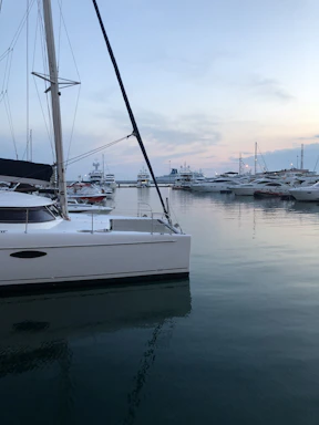 Elegant luxury yacht docked at sunset with calm sea and clear sky.