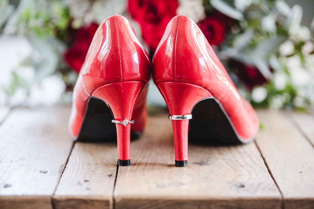 pair of red patent leather heels on wooden surface