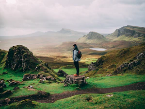 standing woman with backpack facing mountains