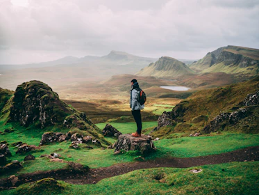 standing woman with backpack facing mountains