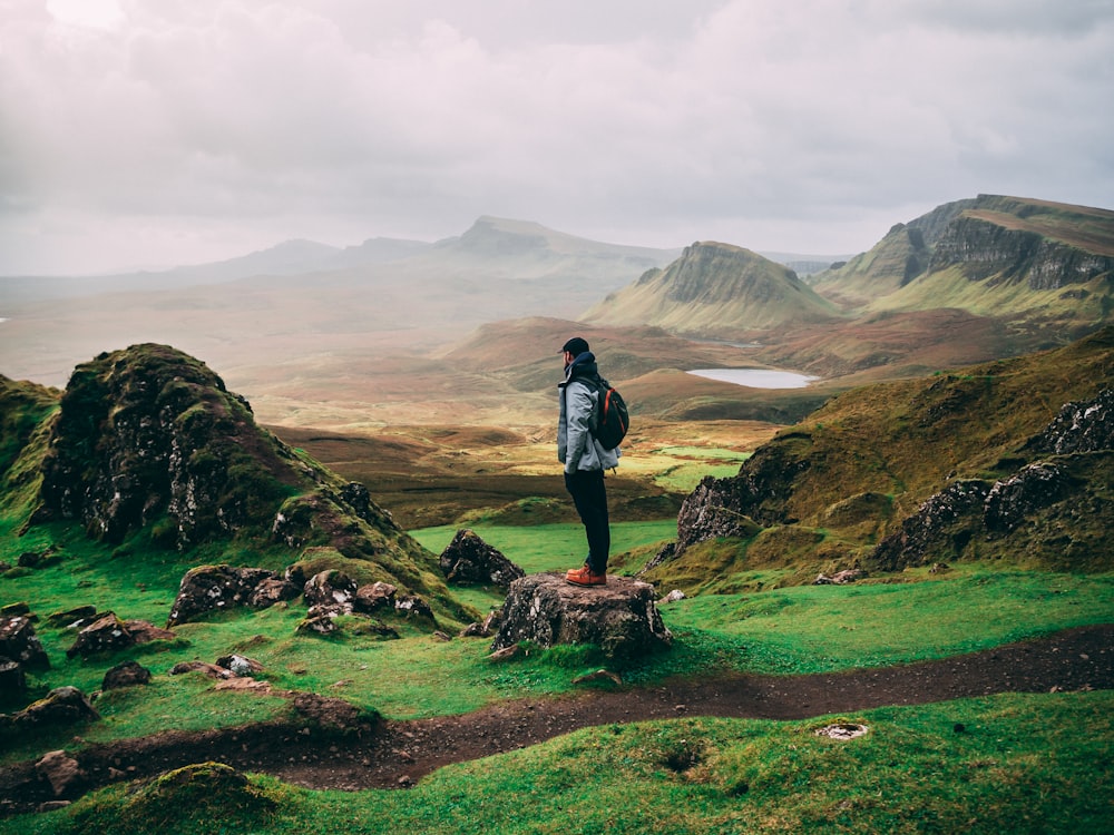 standing woman with backpack facing mountains