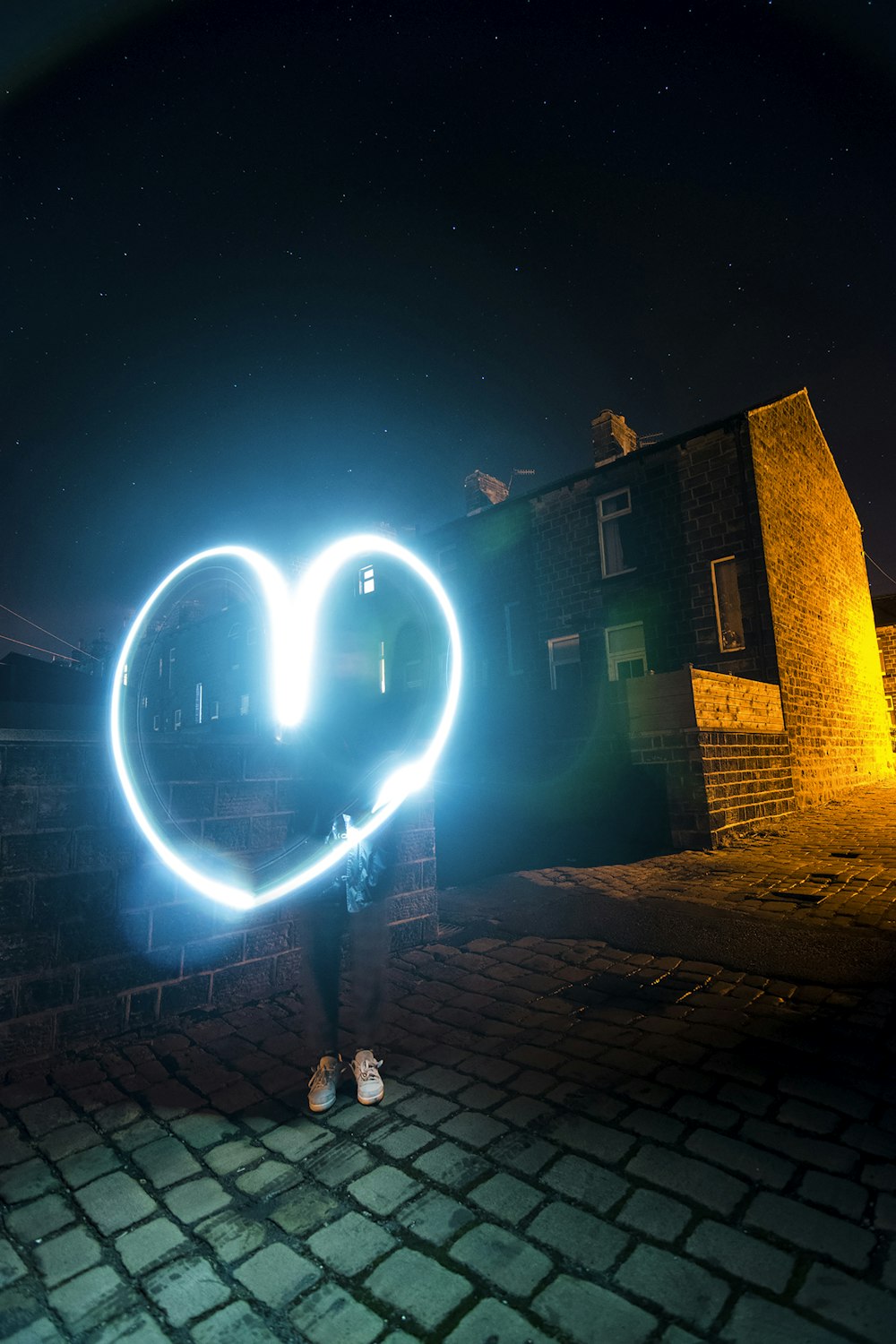 person holding heart wool fire beside building during nighttime