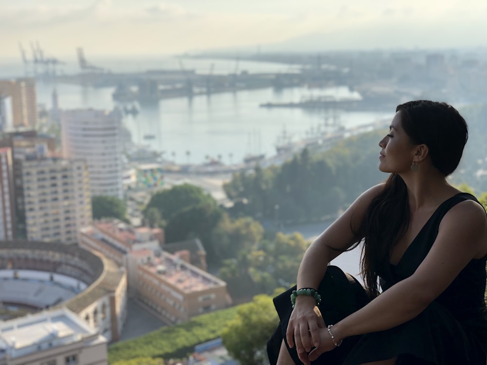 mujer sentada frente a los edificios en la fotografía de enfoque selectivo