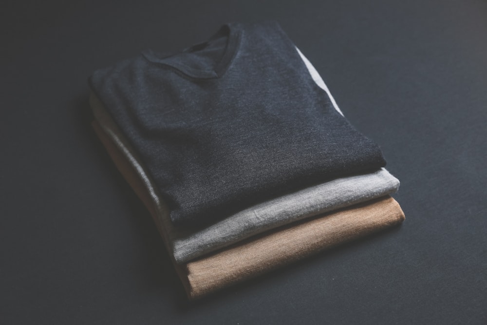 three black,grey,and brown V-neck shirt on black surface