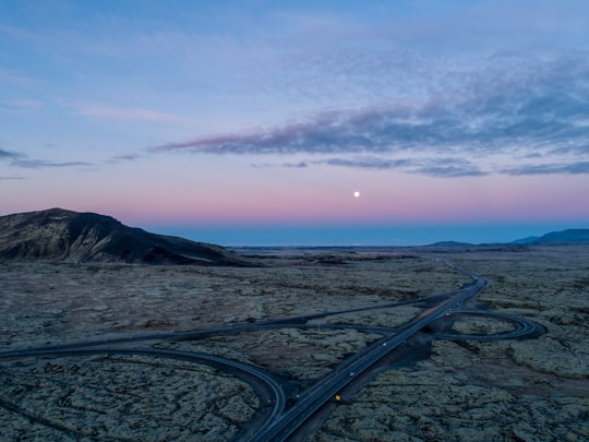 concrete roadway front of field under blue sky in Suðurlandsvegur Iceland