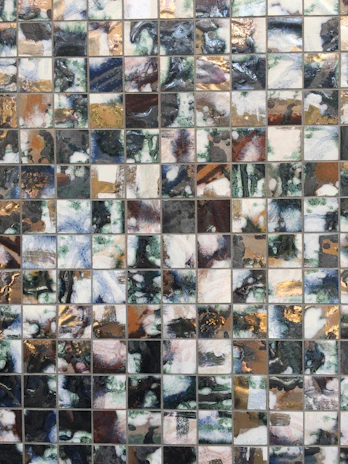Mosaic art piece featuring shimmering glass tiles in gold and cream hues, reflecting light beautifully.