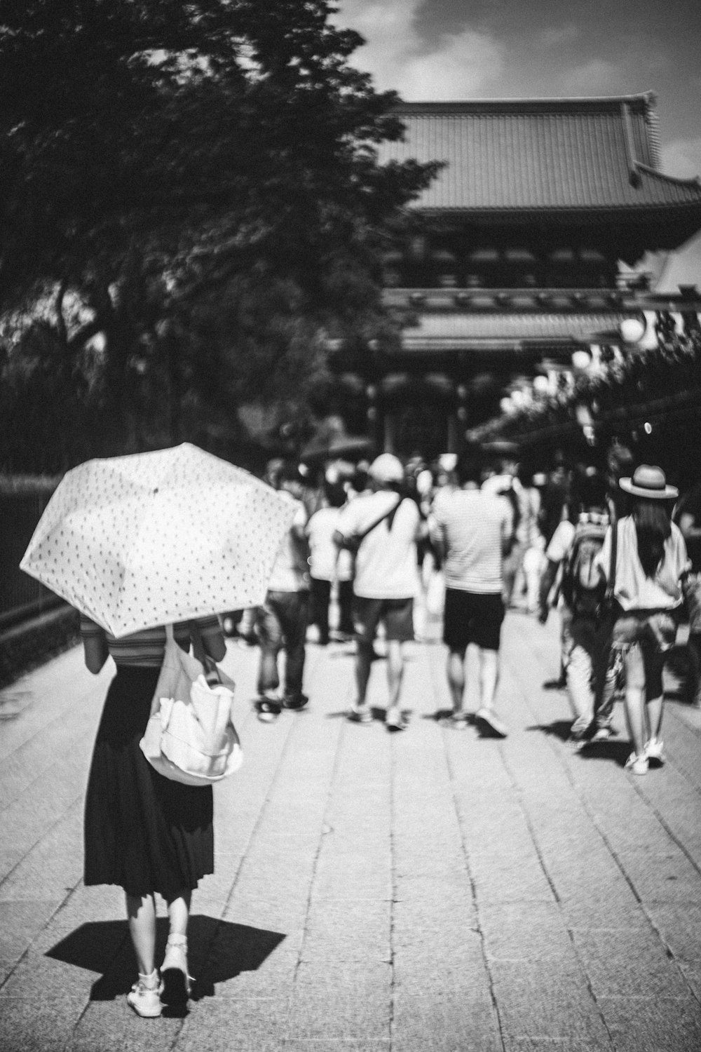 Fotografía en escala de grises de mujer con paraguas caminando