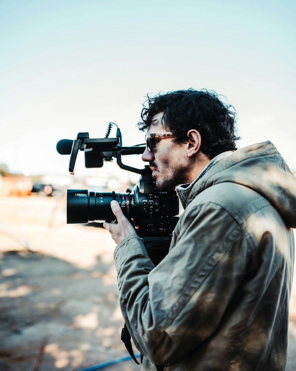 homme en manteau brun tenant une caméra vidéo sur la photographie sélective