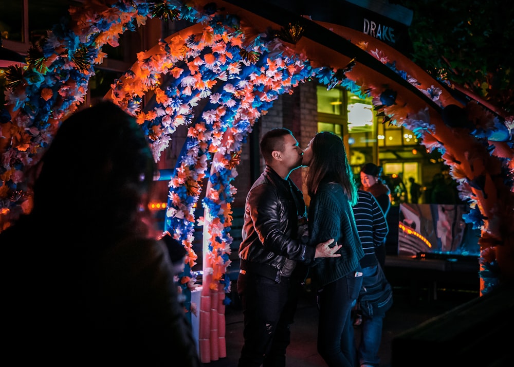 man and woman kissing under flower gazebo