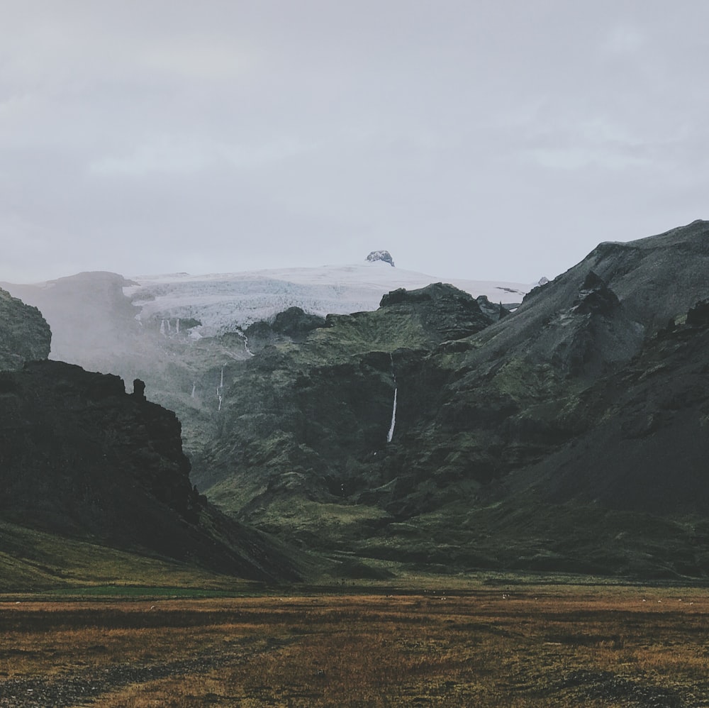 brown field under mountain