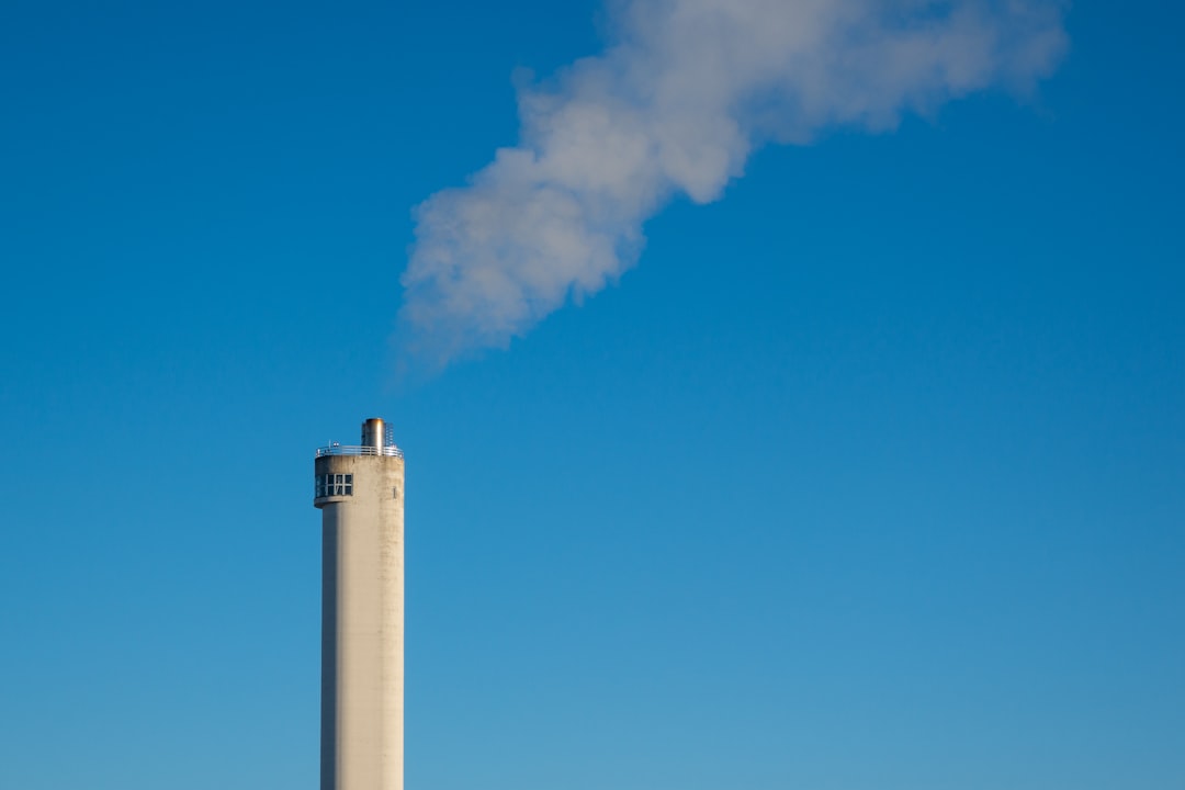 white concrete tower with smoke under blue sky