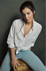 woman in white dress shirt sitting on brown wooden stool