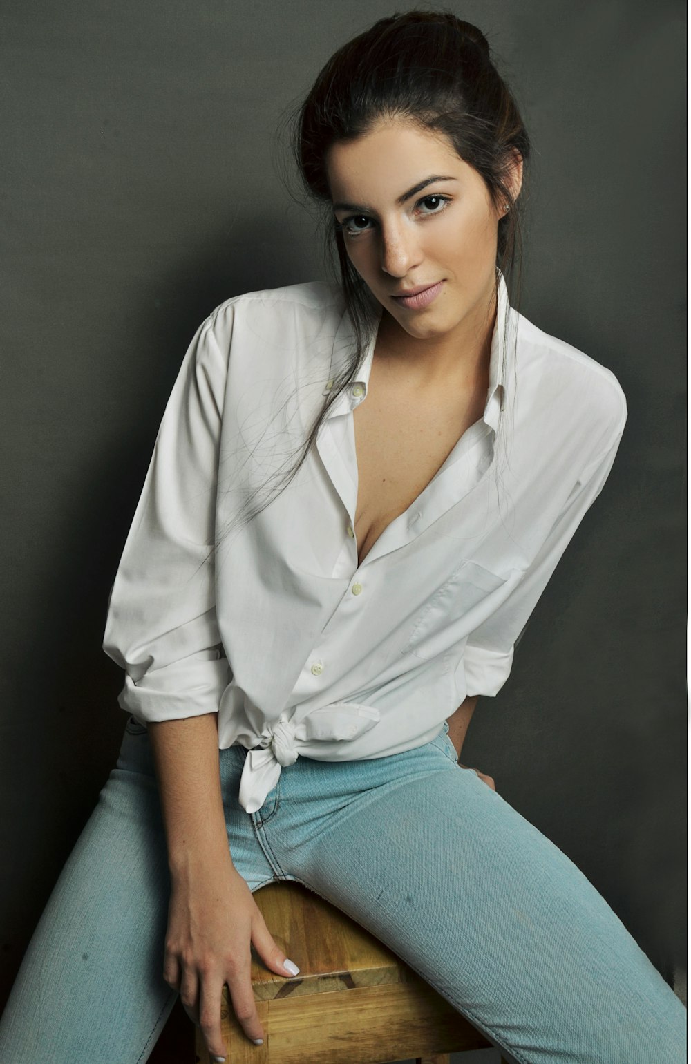 woman in white dress shirt sitting on brown wooden stool