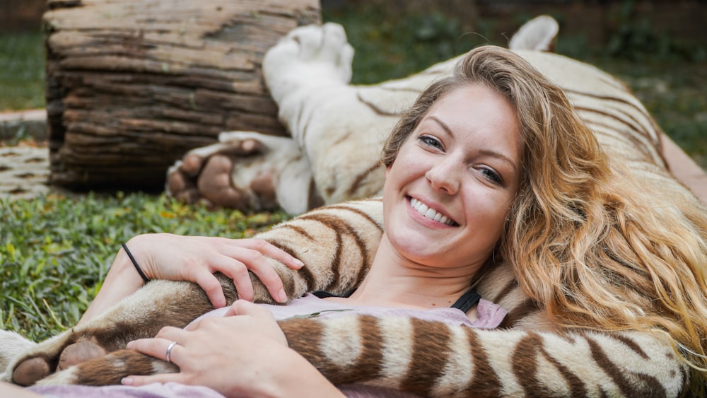 woman beside brown lion lying on grass field