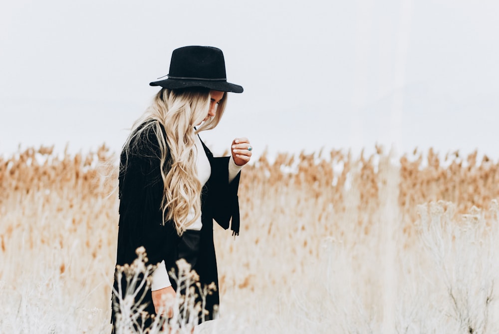 woman in black suit standing surrounded by brown plants