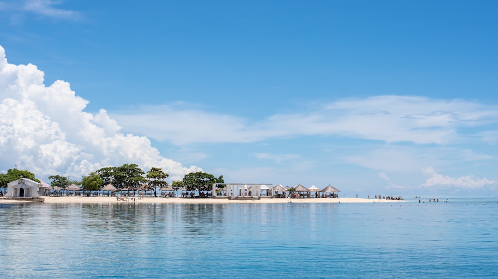 green trees and huts on white sand island surrounded by sea water during daytime