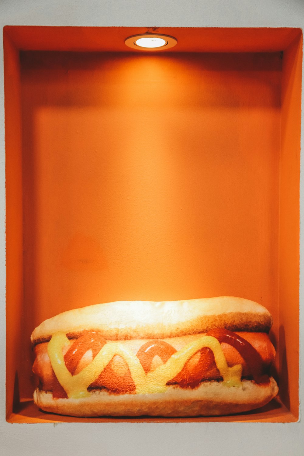 hotdog in bun with ketchup and mustard inside lighted box