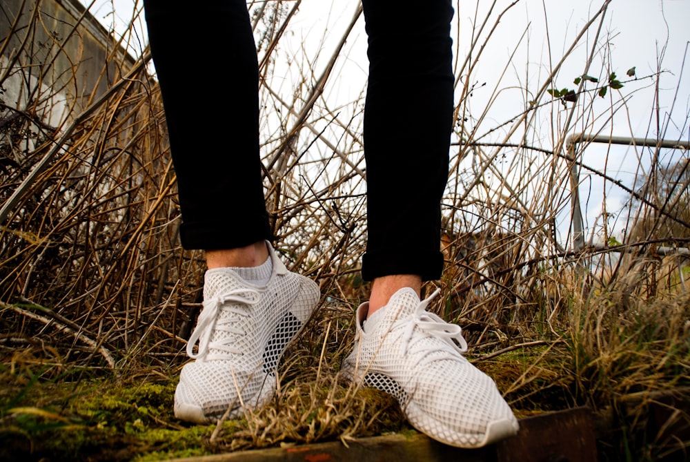 person in black pants and pair of grey low-top sneakers during daytime