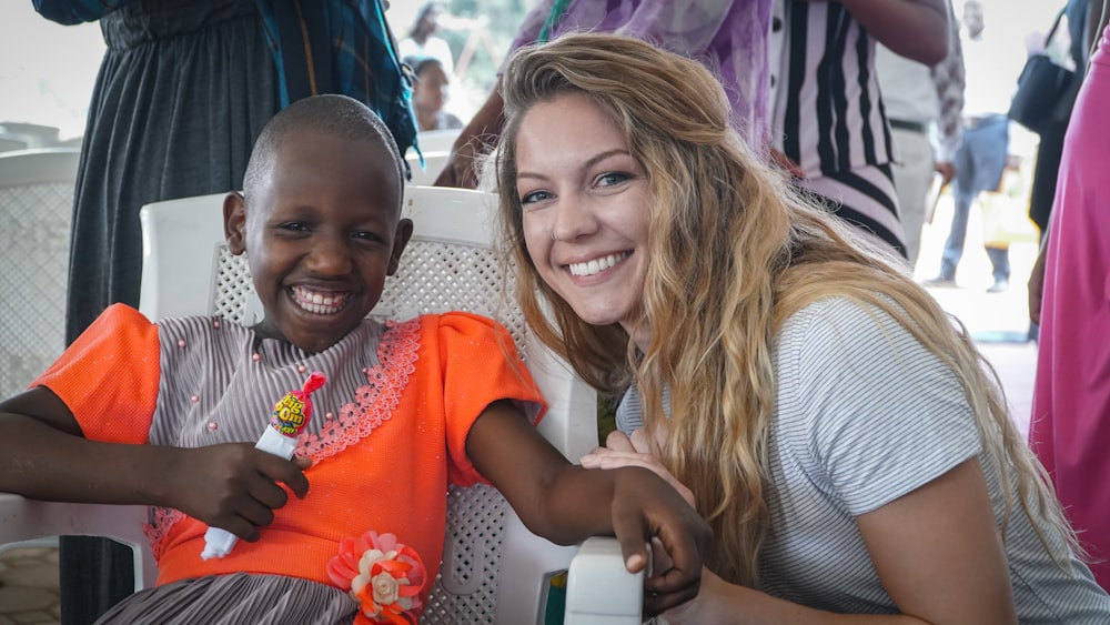 woman in white shirt beside girl in orange shirt