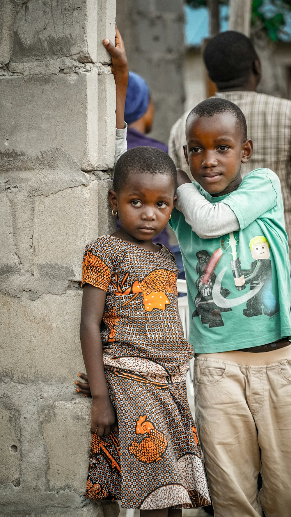 two children learning on wall