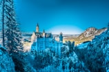 white castle on snow mountain under clear blue sky