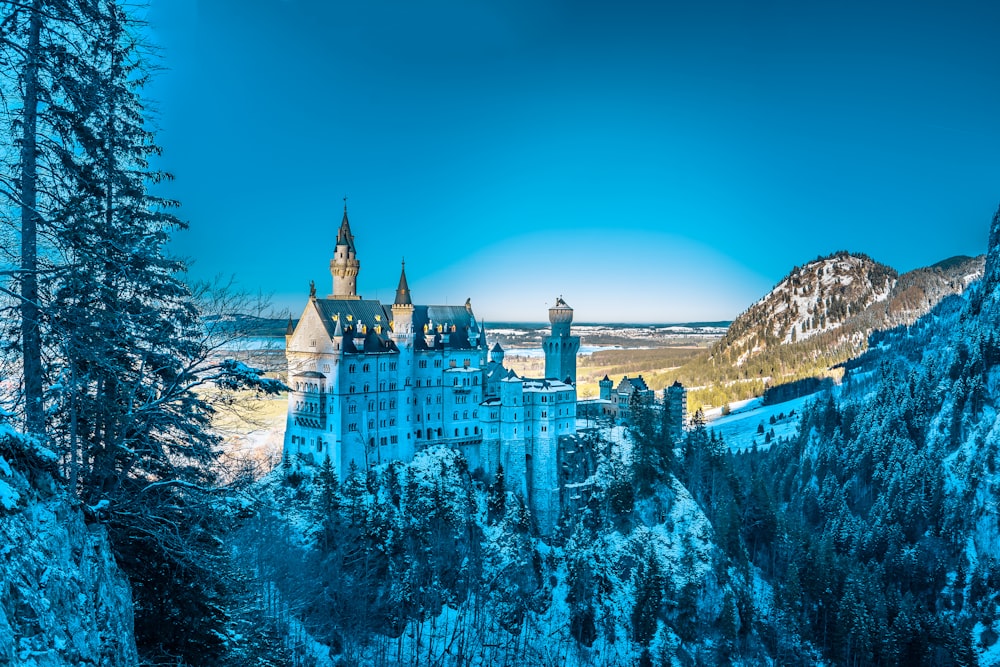 Castillo blanco en la montaña nevada bajo un cielo azul claro