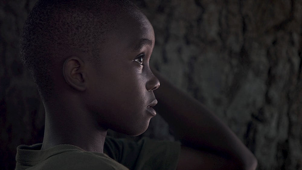 boy wearing grey shirt while touching his head